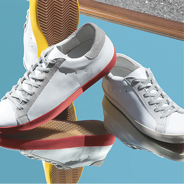 White leather sneakers with red and silver sole units against a blue background